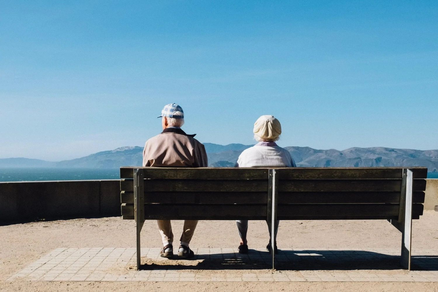 Pension member locate Two pensioners sitting on a bench with amazing Mountain View to show the Pension member tracing service