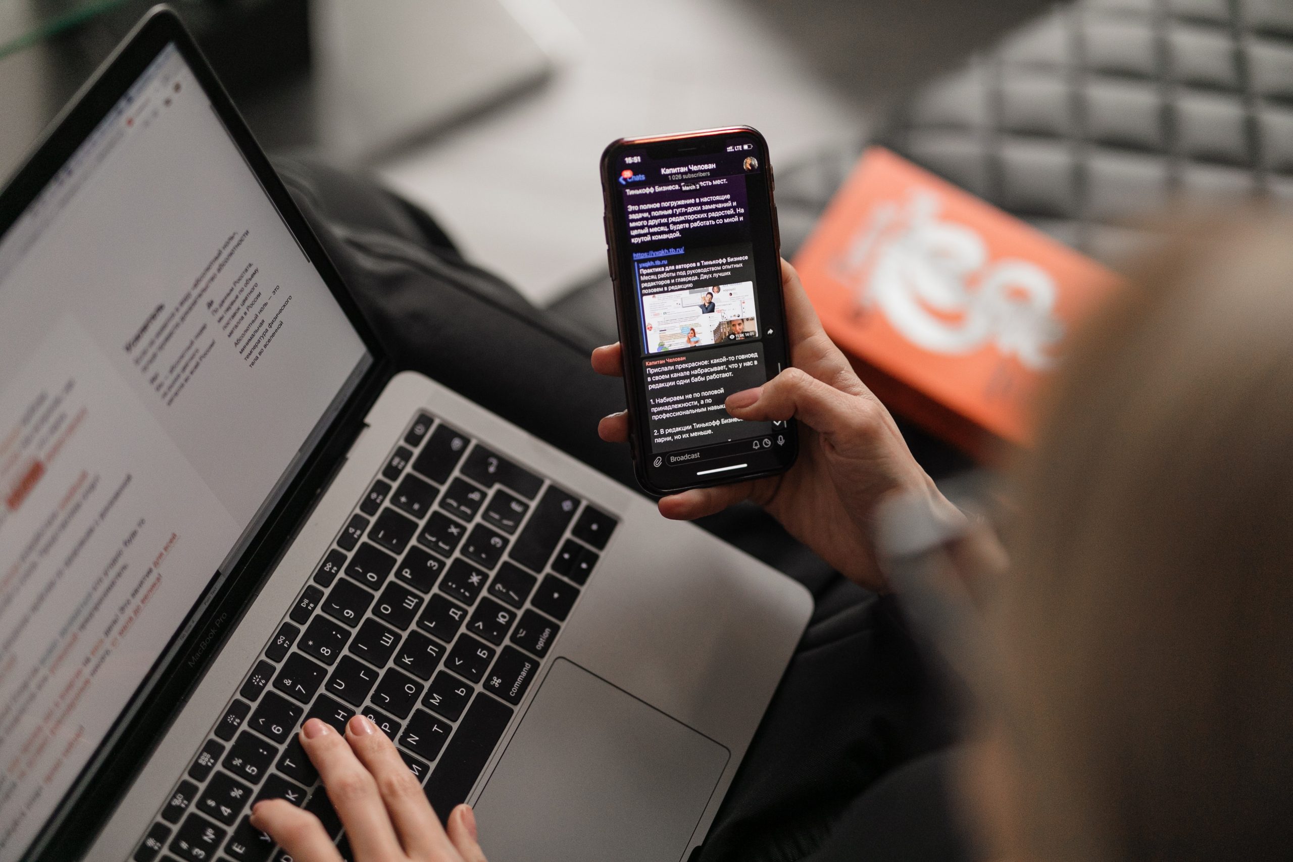 Find UK People private investigator sitting at a laptop looking at phone to research who is the owner of a phone number in the UK