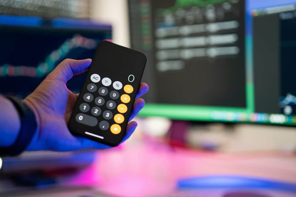 Creditor Business Used Find UK People® to Trace a Debtor and looking at a calculator in front of a screen to evaluate the debt